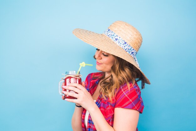 Young sexy woman drinking tasty smoothie on blue background and copy space, vintage outfit, studio lifestyle portrait, dessert