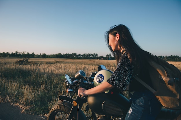 Young sexy woman on a motorcycle in nature on the sunset. Travel Concept.