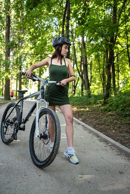 Young sexy woman wear green short dress rides a bicycle in the forest spend free time on summer day Activity lifestyle