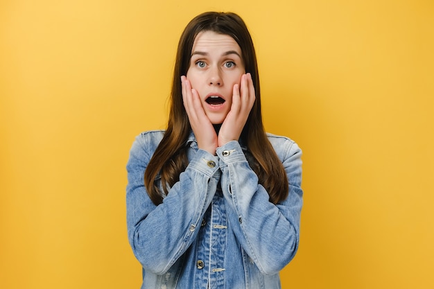 young shocked fascinated woman keeps hands on face