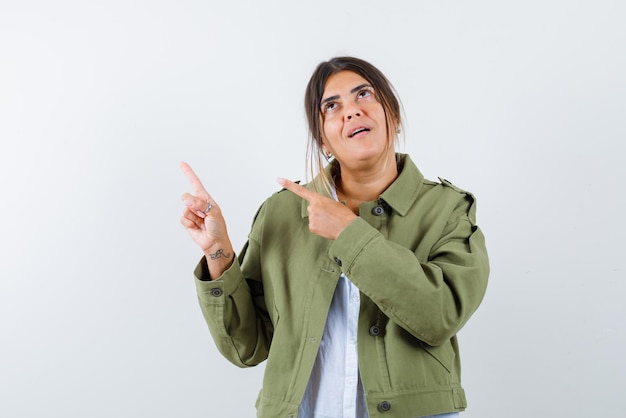 Young showing the left with her fingers and looking up on white background