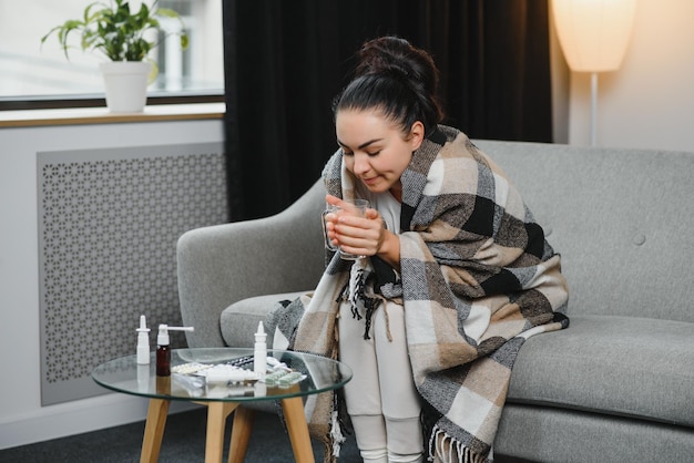 Young sick woman sitting on sofa at home