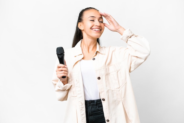 Young singer woman picking up a microphone over isolated white background smiling a lot