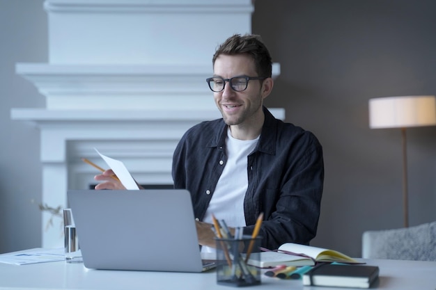 Young sitisfied male entrepreneur in glasses talking speaking during web conference via internet