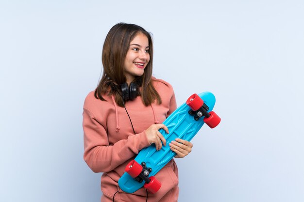 Young skater girl over isolated wall