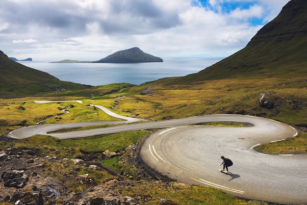 Young skater riding a skateboard through the beatiful scenery of faroe islands