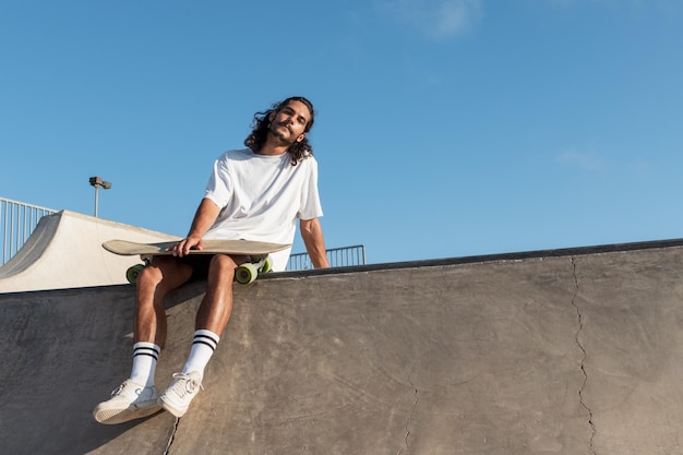 Young skater sitting at the top of the of the skate bowl looking at camera