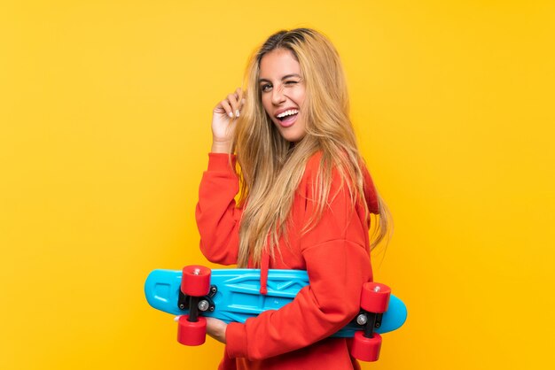 Young skater woman over isolated yellow background