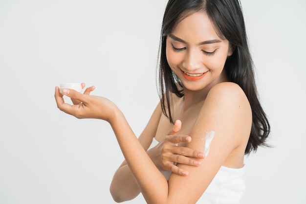 Young skin care asian woman applying body lotion on arm and shoulder