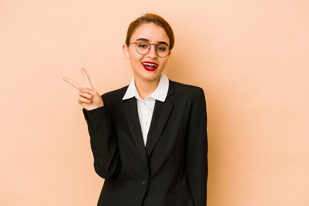 Young skinny caucasian business woman isolated joyful and carefree showing a peace symbol with fingers.