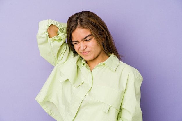 Young skinny caucasian girl teenager on purple background suffering neck pain due to sedentary lifestyle.