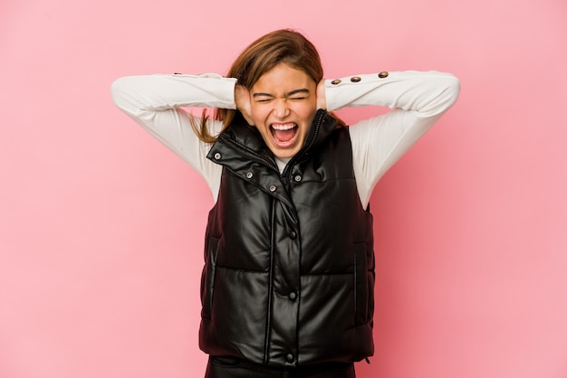 Young skinny caucasian teenager girl covering ears with hands trying not to hear too loud sound.