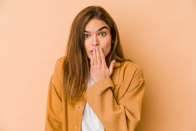 Young skinny caucasian teenager girl shocked, covering mouth with hands, anxious to discover something new.