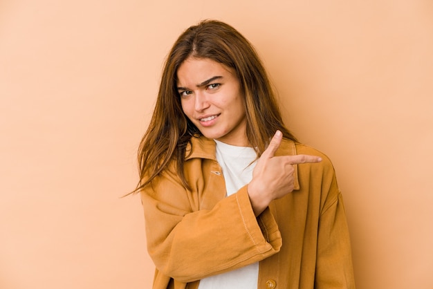 Young skinny caucasian teenager girl smiling and pointing aside, showing something at blank space.