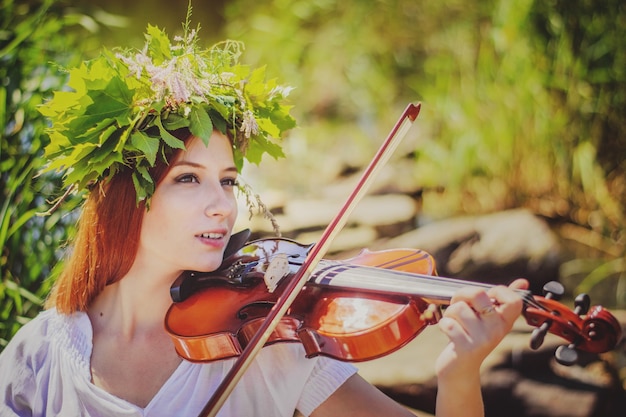 Young slavic girl playing violin in forest