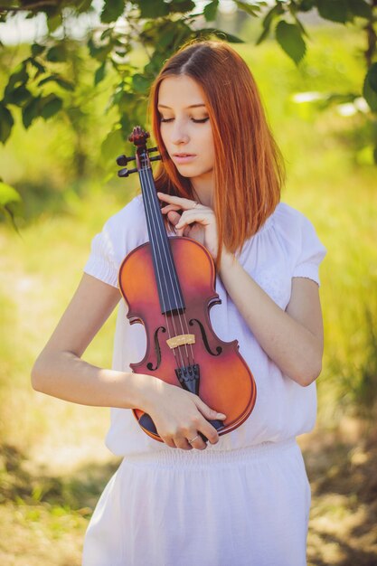 Young slavic girl playing violin in forest