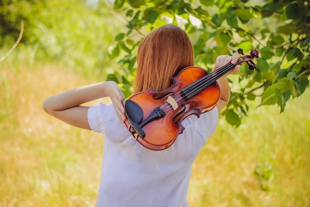 Young slavic girl playing violin in forest