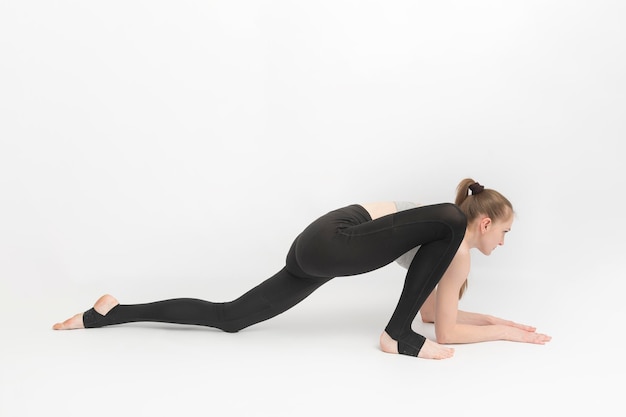 Photo young slender gymnast girl does an exercise to develop flexibility on white background. asanas in yoga.