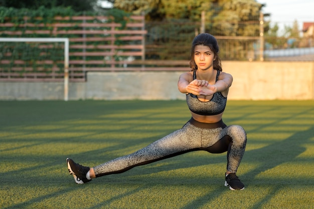 A young slim athletic girl in sportswear with snakeskin prints performs a set of exercises