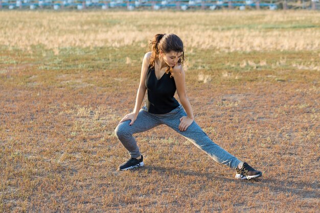 A young slim athletic girl in sportswear with snakeskin prints performs a set of exercises