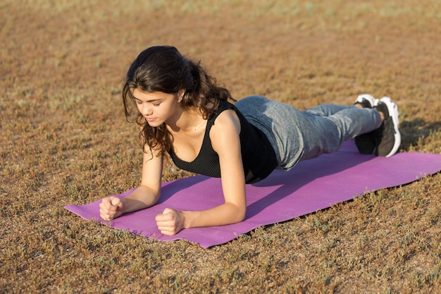 A young slim athletic girl in sportswear with snakeskin prints performs a set of exercises