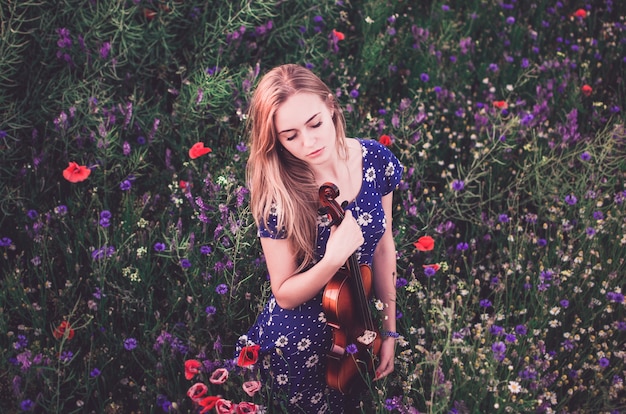 Young slim fair-skinned beautiful blonde woman hugs violin