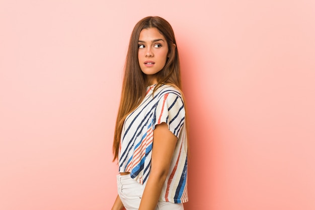 Young slim woman looks aside smiling, cheerful and pleasant.