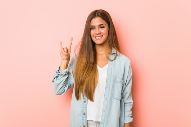 Young slim woman showing a horns gesture as a revolution concept.