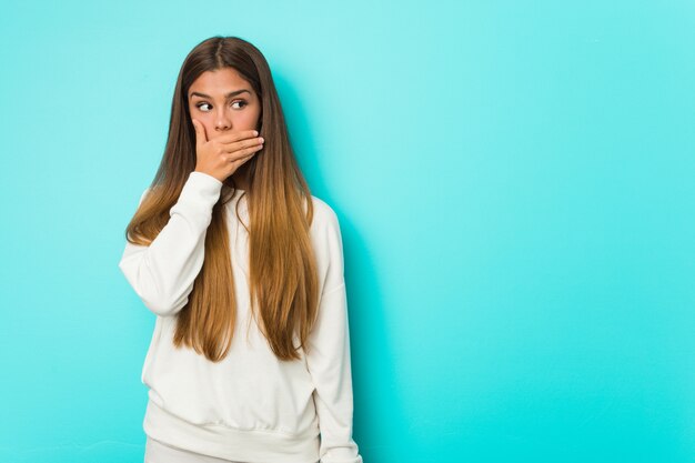 Young slim woman thoughtful looking to a copy space covering mouth with hand.