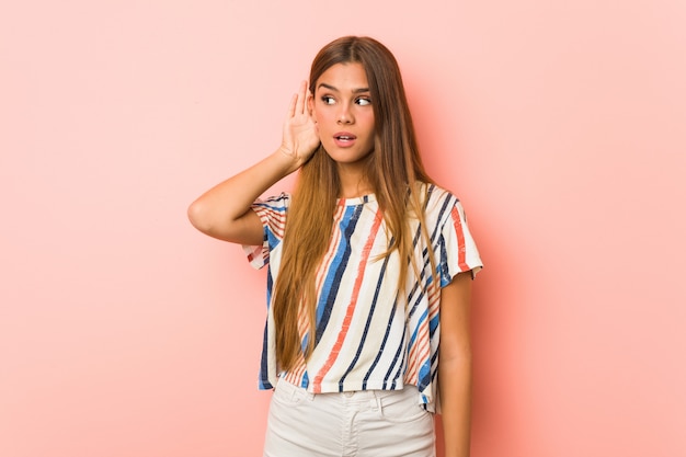 Young slim woman trying to listening a gossip.