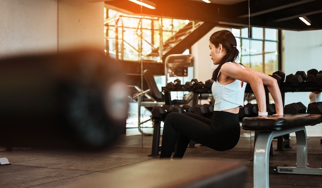 Young slim woman working out on exercise chair in fitness gym