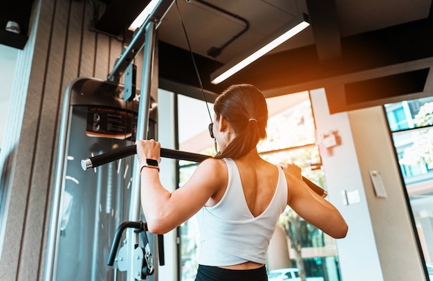 Young slim woman working out on training apparatus in fitness gym