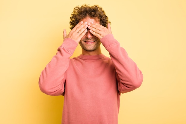 Photo young smart caucasian man on yellow background afraid covering eyes with hands