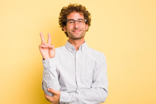 Photo young smart caucasian man on yellow background showing number two with fingers