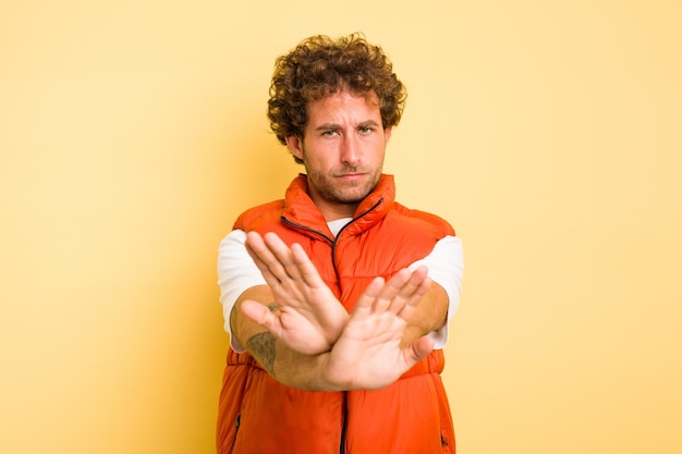 Photo young smart caucasian man on yellow background standing with outstretched hand showing stop