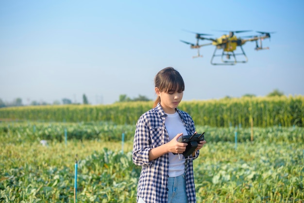 A young smart farmer controlling drone spraying fertilizer and pesticide over farmland