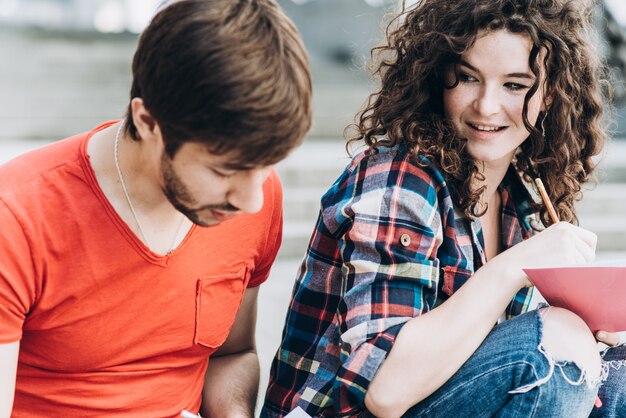 Young smart people are using gadgets and smiling while studying