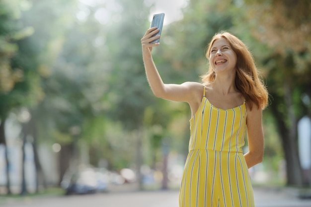 Young smart smiling woman taking a selfie with her cell phone.