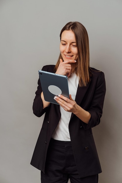 Young smart woman is looking at the tablet and thinking how to fix some issues