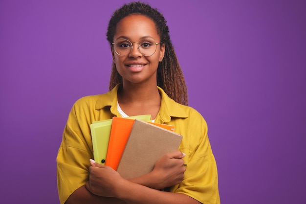 Young smiled african american woman with folders for papers stands in studio