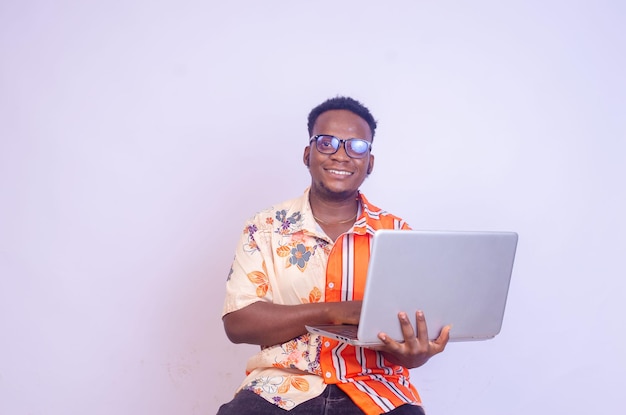 Young smiling african american man sitting and using laptop computer isolated over white background excited