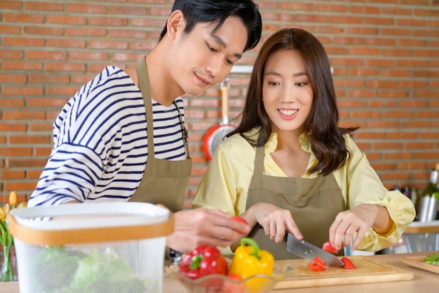 Young smiling asian couple wearing an apron in the kitchen room cooking concept