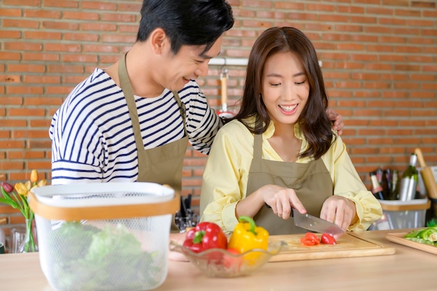 Young smiling asian couple wearing an apron in the kitchen room cooking concept