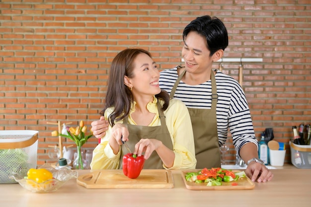 Young smiling asian couple wearing an apron in the kitchen room cooking concept