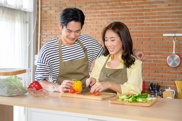 Young smiling asian couple wearing an apron in the kitchen room cooking concept