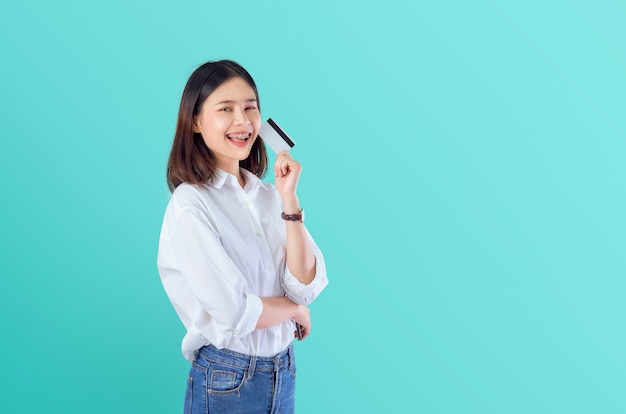 Young smiling Asian woman holding credit card blank with crossed arms 