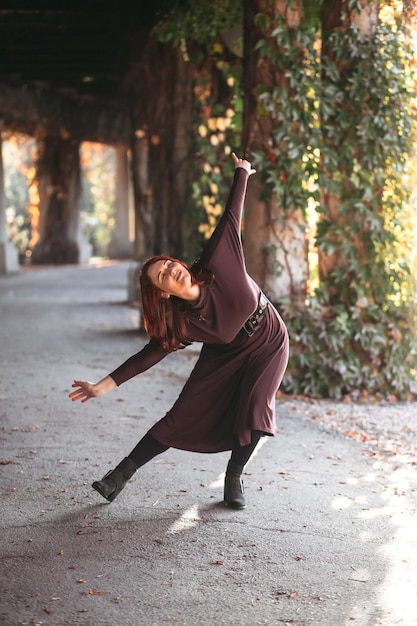 Young smiling attractive woman in morning sunrise dancing in dress healthy lifestyle having fun