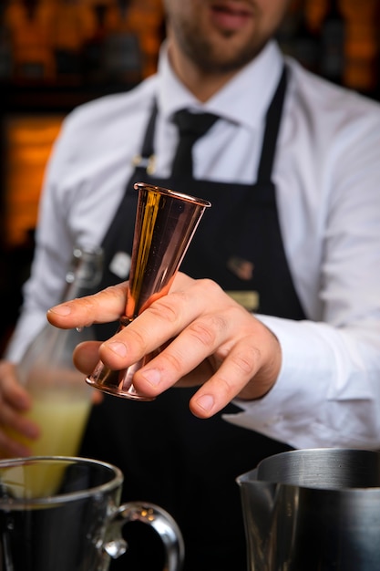 Young smiling bartender in a black apron prepares mulled wine