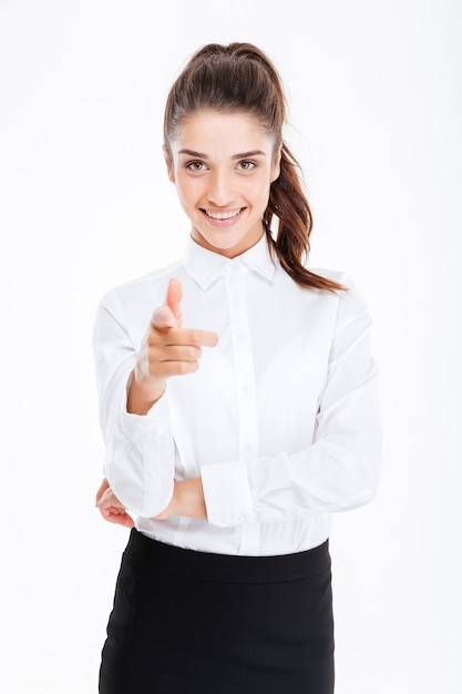 Young smiling beautiful businesswoman pointing at front isolated on the white wall