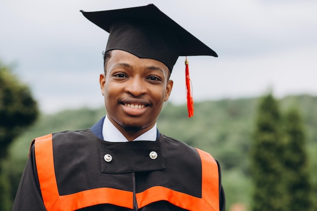 Young smiling black male on his graduation day in university Education qualification and gown concept